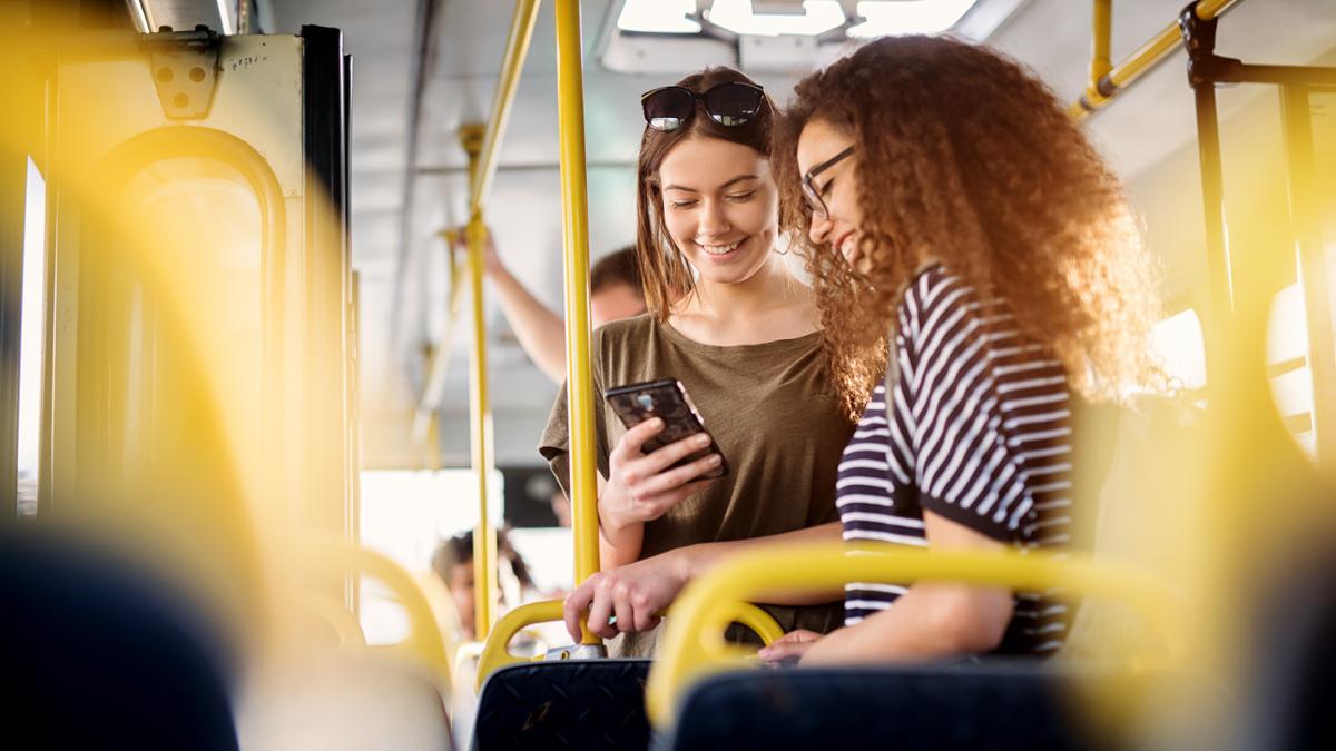 Two people on public transportation sharing a phone